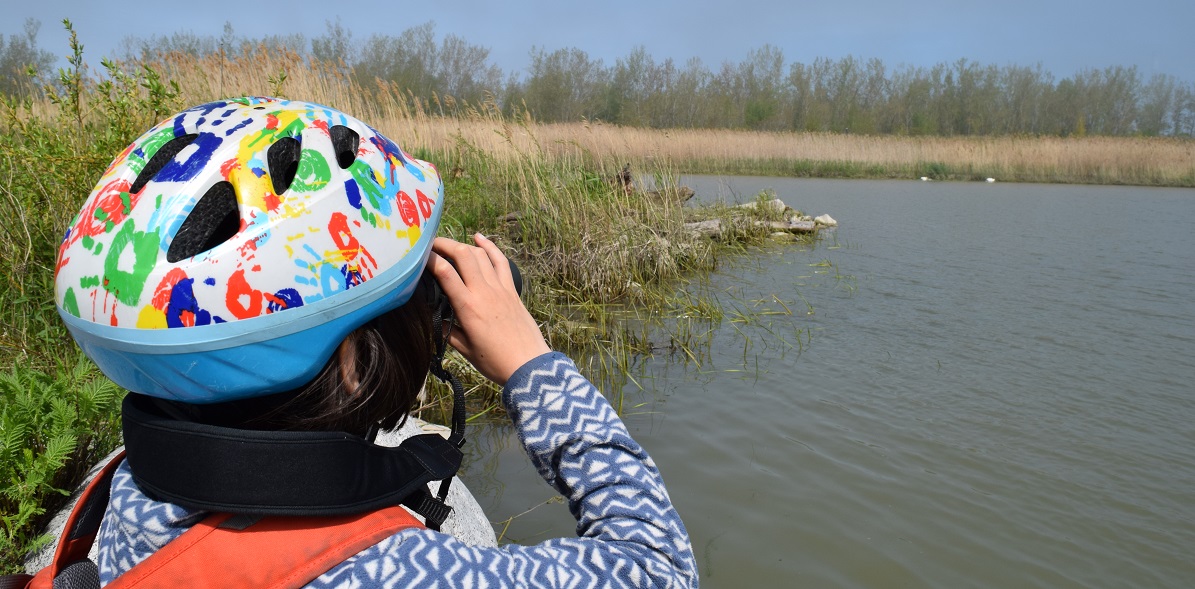 a summer camper uses binoculars to search for wildlife at Tommy Thompson Park