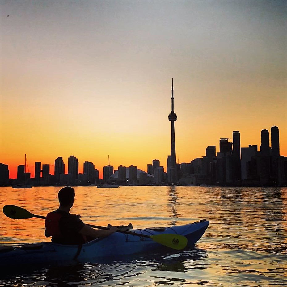 Kayaker looking at the sunset over the city of Toronto and CN Tower