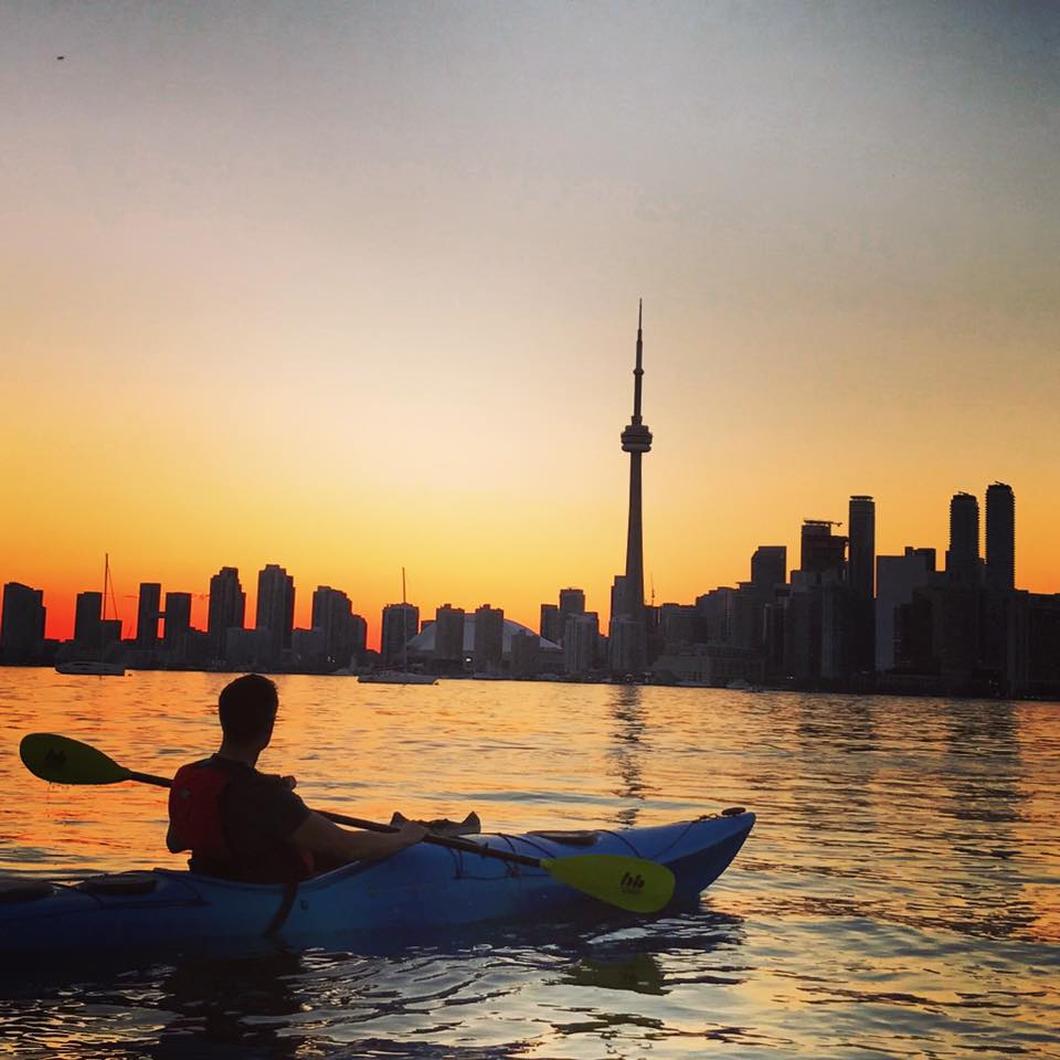 Kayaker looking at the sunset over the city of Toronto and CN Tower