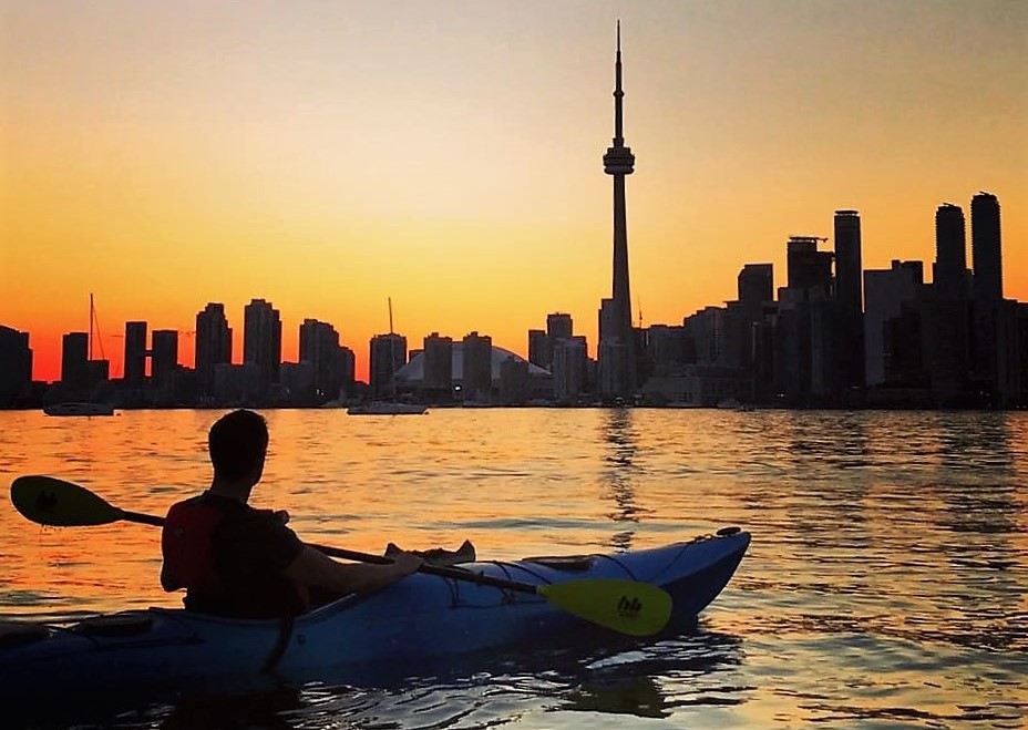 Paddler sitting in kayak looking at Toronto sunset