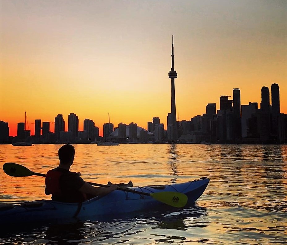 Paddler sitting in kayak looking at Toronto sunset